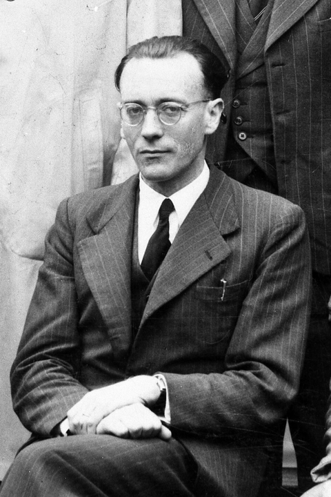 Portrait en noir et blanc de Roger Bouvet en costume et portant des lunettes